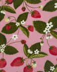 pink fabric with red strawberries, white flowers and green leaf pattern. 