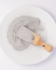 grey grains on wooden spoon on white plate